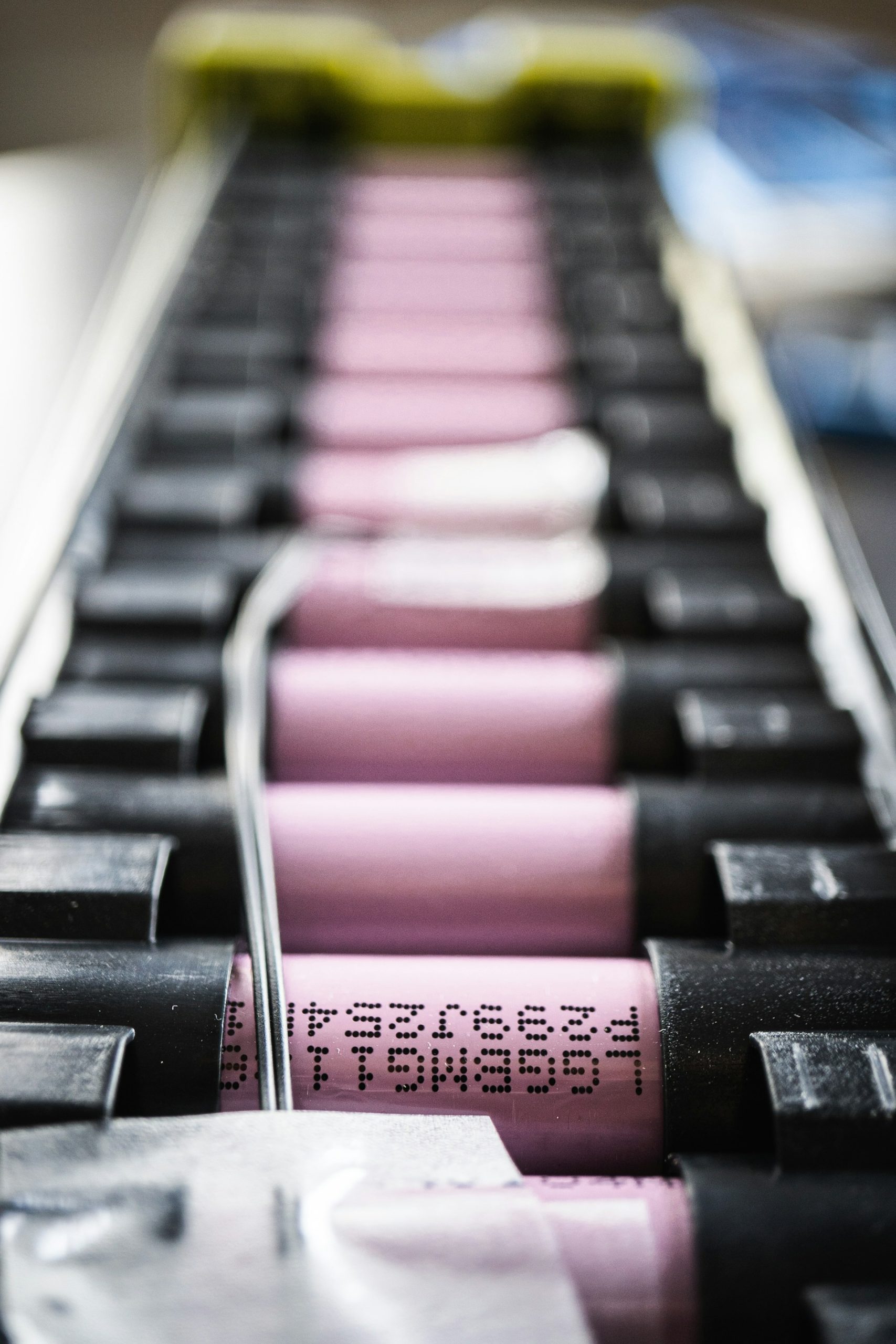 A macro close-up of individual lithium-ion battery cells aligned in a mounting rack, illustrating the precision engineering and technical components that power VH Energy’s advanced residential and commercial battery storage systems.