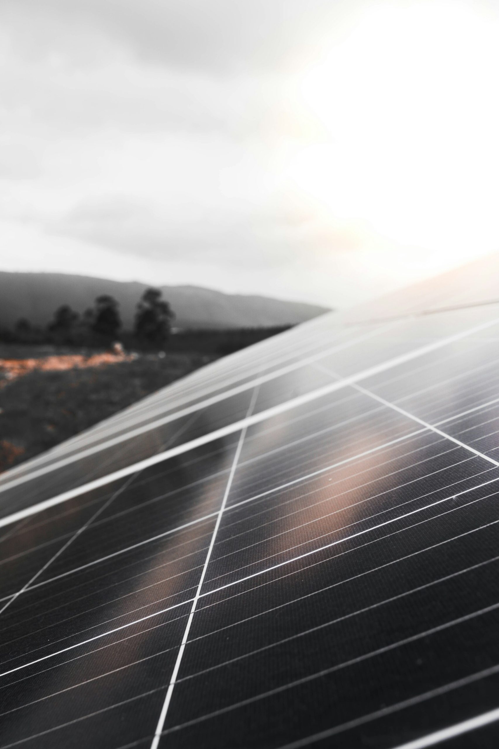 A professional installation of solar photovoltaic panels on a residential roof in Vermont, with a scenic backdrop of New England mountains and trees, engineered by VH Energy for remote grid resilience and energy independence.